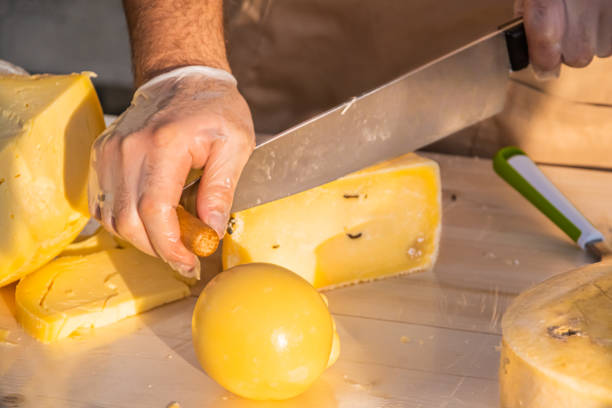 istock Shopkeeper's hands cutting a head of cheese 1320794240