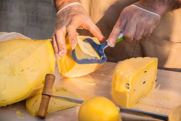 istock Shopkeeper's hands cutting a head of cheese 1320794301