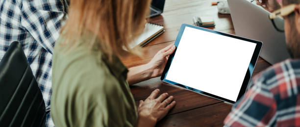 istock Mockup image of a female hands holding digital tablet with empty blank screen on wooden table. Copy space 1320796889