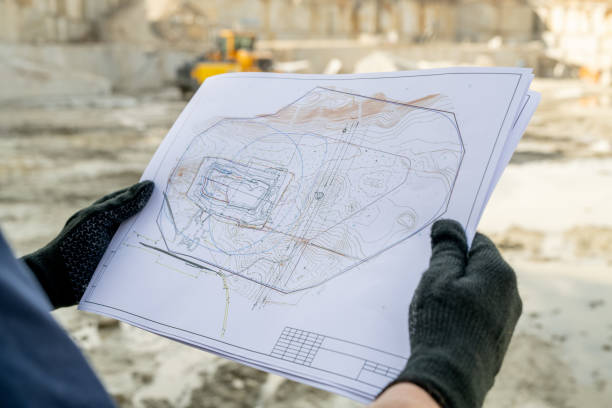 istock Gloved hands of builder holding paper with sketch 1320797848