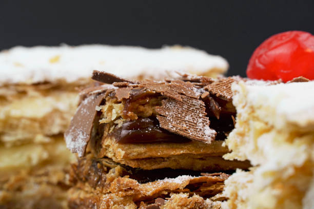 istock Puff pastry cakes with powdered sugar and cream and another with chocolate and a cherry on top on the wooden table. Close up. Selective focus 1320799617
