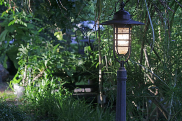 istock Lampost with lamp light on in a garden in daylight 1320800276