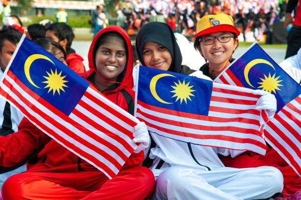 Three young smiling Malaysian girls holding Malaysian flags and have high patriotism spirit for Hari Merdeka Three young Malaysian Malay, Chinese and Indian participants in sport uniforms holding Malaysian flags celebrating the Independence day of Malaysia at Merdeka Square, Kuala Lumpur, Malaysia. merdeka square stock pictures, royalty-free photos & images
