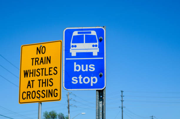 Railway Crossing and Bus Stop sign together against a blue sky