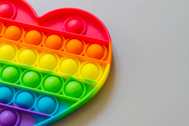 istock Pop it, A relaxing rainbow-colored toy for Tapping heart-shaped bubbles with your fingers 1320801586