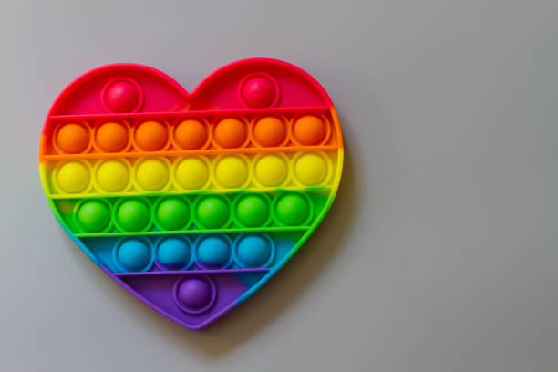 istock Pop it, A relaxing rainbow-colored toy for Tapping heart-shaped bubbles with your fingers 1320801609