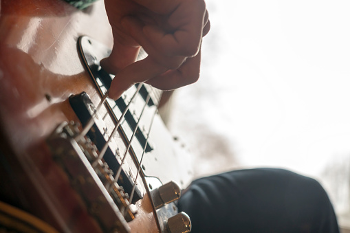 Low angle view on mans fingers playing electric guitar