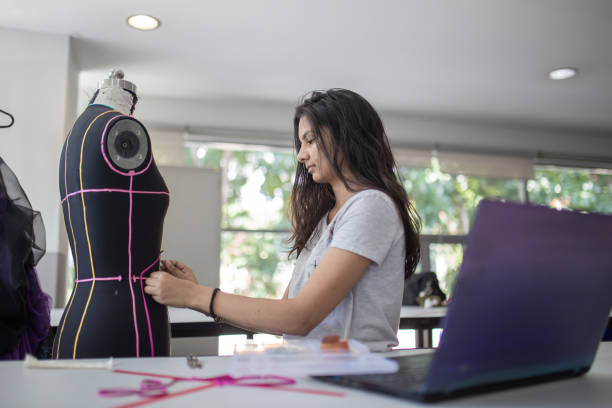 Female college fashion student attending class in the classroom working on their fashion design Female college fashion student attending class in the classroom working on their fashion design textile industry stock pictures, royalty-free photos & images