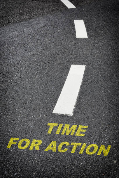 istock Time for action written on black asphalt road and white marking lines 1320809511