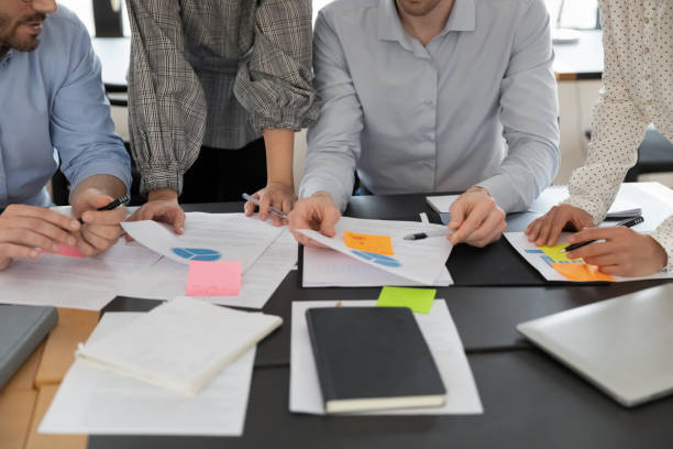 istock Close up cropped of diverse employees working with project documents 1320811374