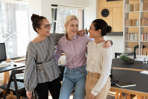 istock Overjoyed successful diverse businesswomen hugging, standing in modern office 1320811444