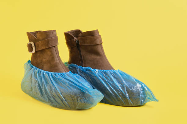 istock brown suede winter boots in blue plastic shoe covers on a yellow background 1320811677