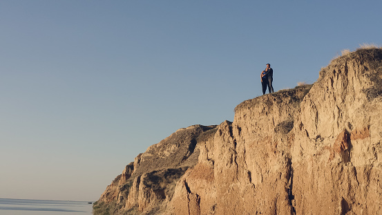 The man and woman standing on the mountain top near the sea