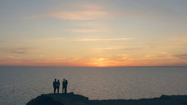 cztery osoby stojące na skalistym brzegu morza - sunrise beach couple hiking zdjęcia i obrazy z banku zdjęć