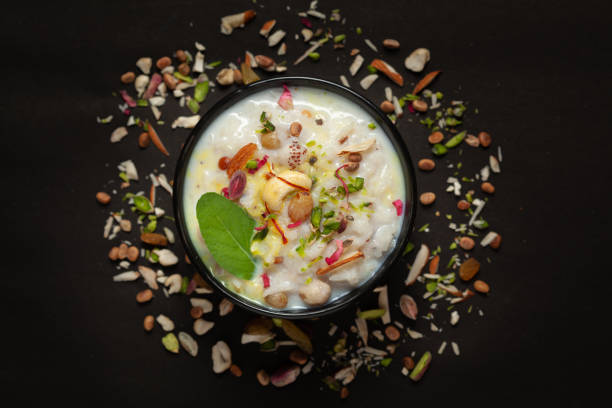 primo primo piatto di riso cremoso kheer(khir) guarnito con foglia di basilico, zafferano e frutta secca. dessert delizioso indiano. servito in una ciotola nera di ceramica. - almond bowl ceramic food foto e immagini stock