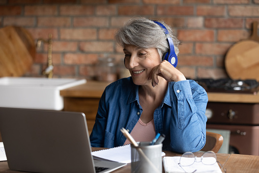 Anciana con auriculares participa en conversación de videollamada photo