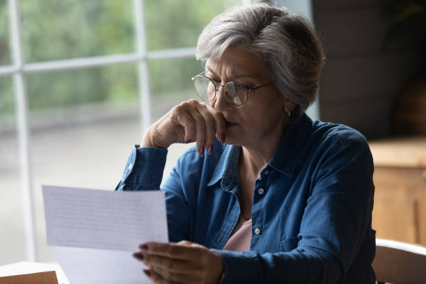 istock Middle aged female reading letter looking concerned 1320817132