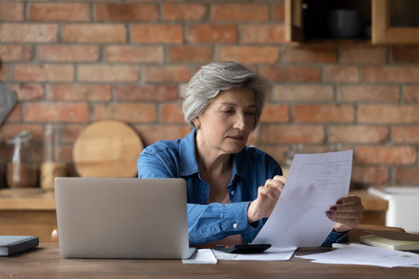 istock Middle-aged woman holding document checking bank statement 1320817150