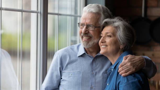 istock Happy mature spouses hugging looking out the window 1320817151