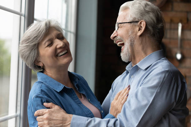 istock Middle-aged untroubled couple hugging laughing while standing indoor 1320817167