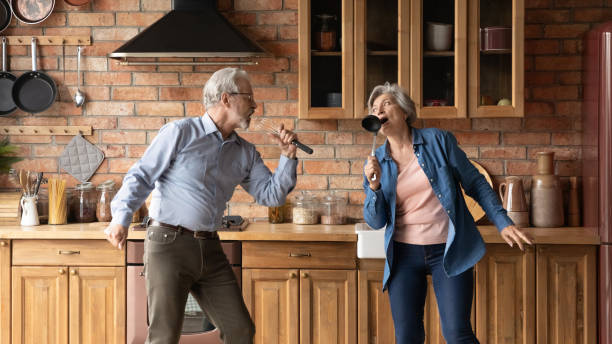 istock Funny mature spouses having fun singing together in kitchen 1320817170