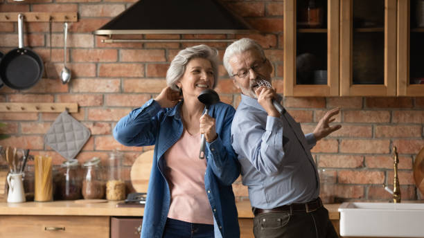 istock Happy middle aged spouses dancing singing in kitchen 1320817173