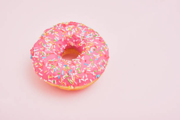 istock Donut with pink icing and pastry sprinkles on a pink background 1320817547
