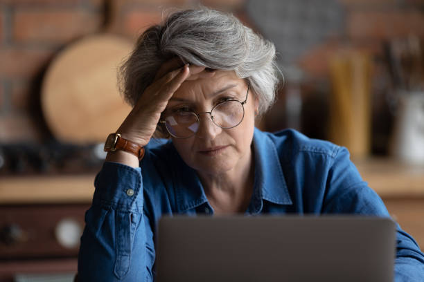 mature woman feels confused experiencing difficulties with laptop usage - old senior adult women tired imagens e fotografias de stock