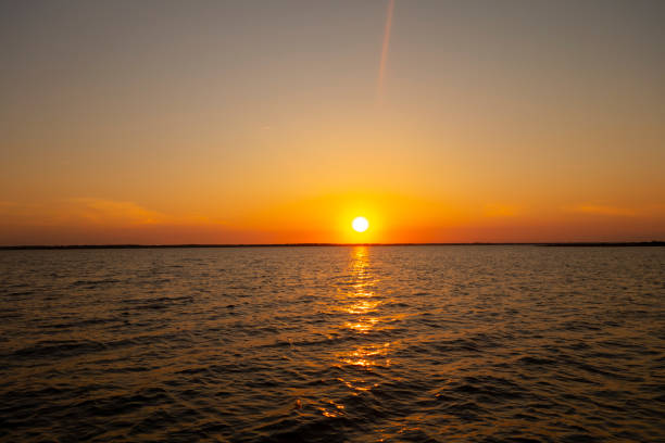 riflesso del tramonto all'alba sull'acqua di mare con cielo giallo-arancio - city of sunrise reflection sunrise summer foto e immagini stock