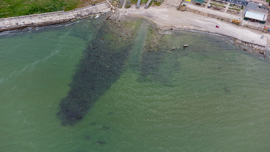 Seashore in an industrial area. Waste water discharge pipes into the sea. Aerial view