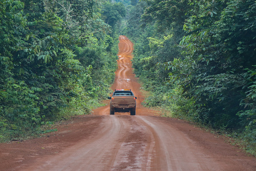 Jacareacanga, Para, Brazil - May 18, 2021: Car traveling on an unpaved stretch of the trans-amazon highway (BR-230), surrounded by dense Amazon forest, between the cities of Itaituba and Jacareacanga.