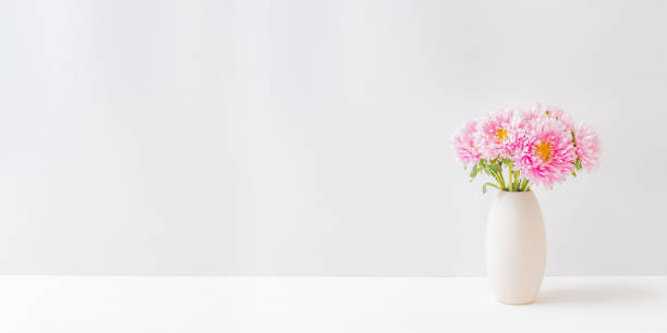 istock Pink flowers in a vase on a light background at home interior. Modern interior design 1320835436