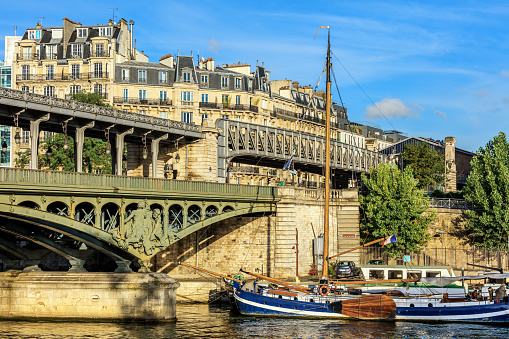 View of the Pont de Bir-Hakeim from the Ile aux Cygnes. Sailboat and buildings of Paris are visible in the background. Paris, France