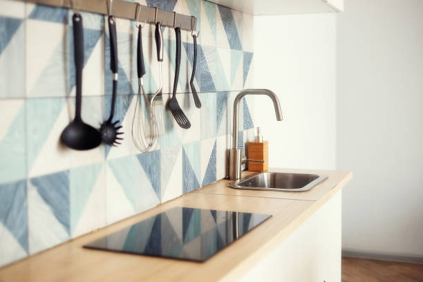 istock Kitchen spatulas handing on railing on a tiled wall with a blue geometric pattern in the modern designed kitchen room in a Scandinavian stayle. Kitchenware object and interior photo. 1320839995
