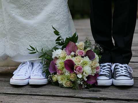 Partial shot bridal couple with sneakers and bridal bouquet in the middle