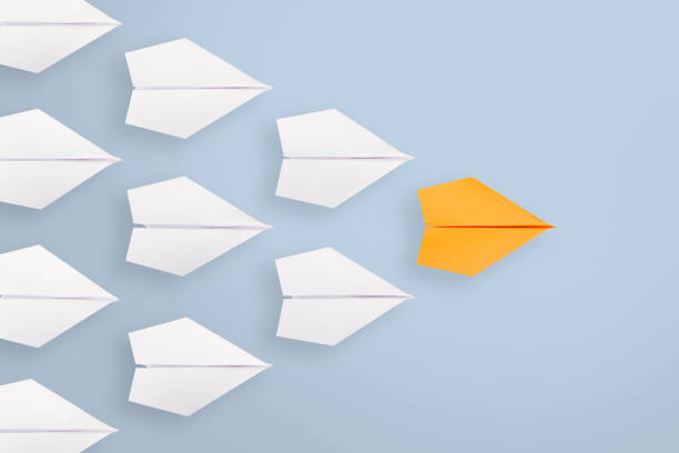 istock Leadership concepts with orange paper airplane leading among white 1320841298