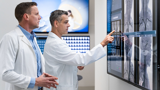 Doctors using modern technology for imaging patients organs. Large touch panel displaying scan results. Examination at specialized medical clinic, diagnosis and healthcare concept.
