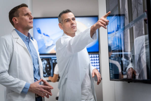 istock Doctor explaining his opinion to colleague. Pointing at large LCD screen. 1320844573