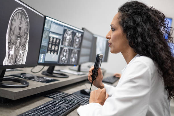 モニターで脳mriを見る女性放射線科医とメモを指示する。 - doctor radiologist computer latin american and hispanic ethnicity ストックフォトと画像