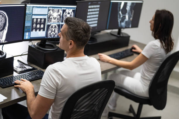 istock Man and woman working side by side on computer. Doctors analyzing MRI scans. 1320844629