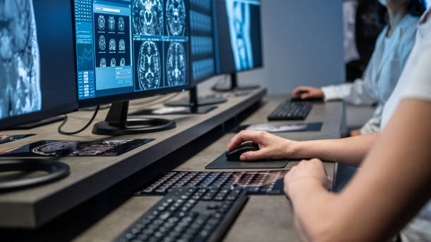 istock Close-up of female hands working with computer. Human brain MRI scans on multiple monitors. 1320844646