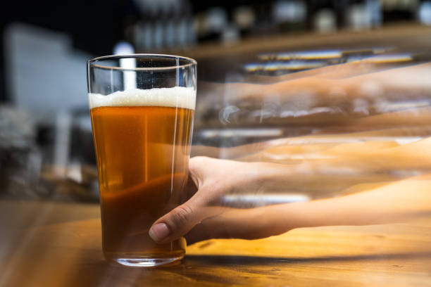 istock Hand holding glass of beer. Multiple exposed hand representing drunk vision. 1320844752