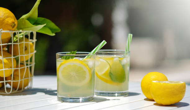 istock Refreshing mojito or lemonade in glasses. Summer yellow fruit cocktail on white table. Hard light harsh shadows.Summer holiday concept. Top view. Trend 2021 1320849888