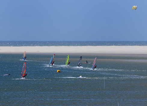 Young People Windsurfing In A Small Bay On The East Frisian Island Borkum On A Sunny Spring Day With A Clear Blue Sky