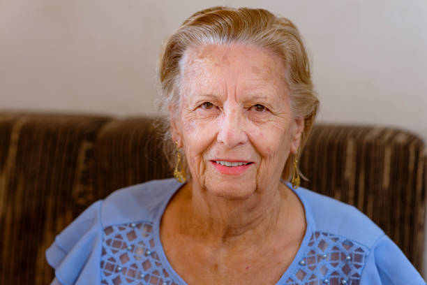 Photo of a senior woman sitting in the garden with raspberry in her hand