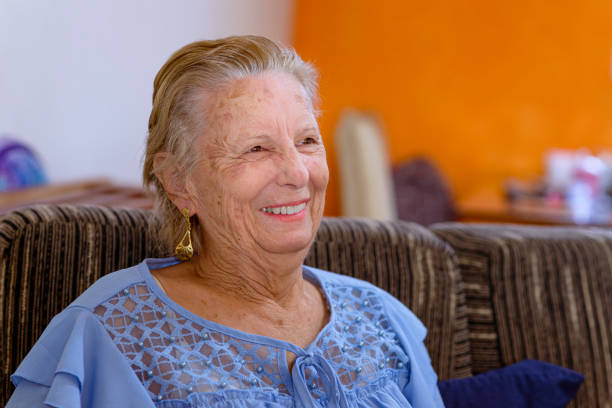 istock Lady sitting on the couch looking at the television and smiling 1320868425