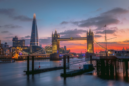 Beautiful during sunrise with illuminated buildings on the River Thames at Tower Bridge and Financial district in City of London, England.