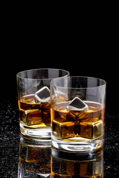 istock Whiskey with steel cooling cubes on dark glass background 1320869363