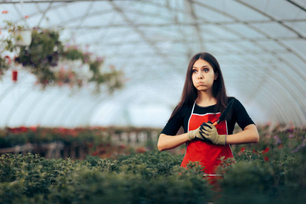 istock Stressed Greenhouse Worker Holding Gardening Tools 1320875661