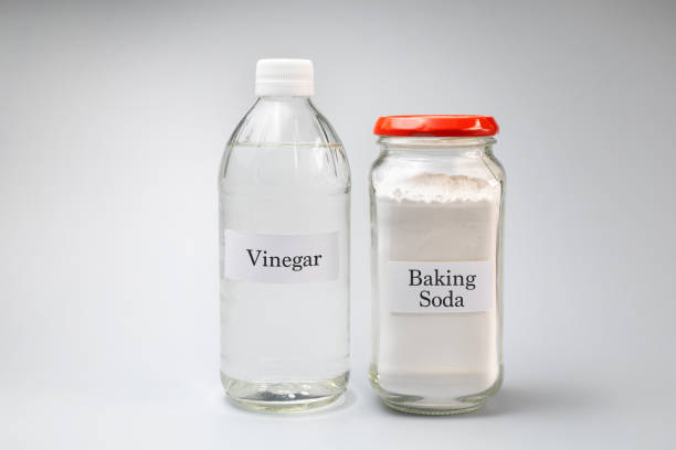 a bottle of vinegar and a jar or baking soda against gray background - vinegar imagens e fotografias de stock